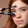 Close-up of a young woman's face with red hair, holding the Motion Beauty Sport Lash Waterproof Mascara.